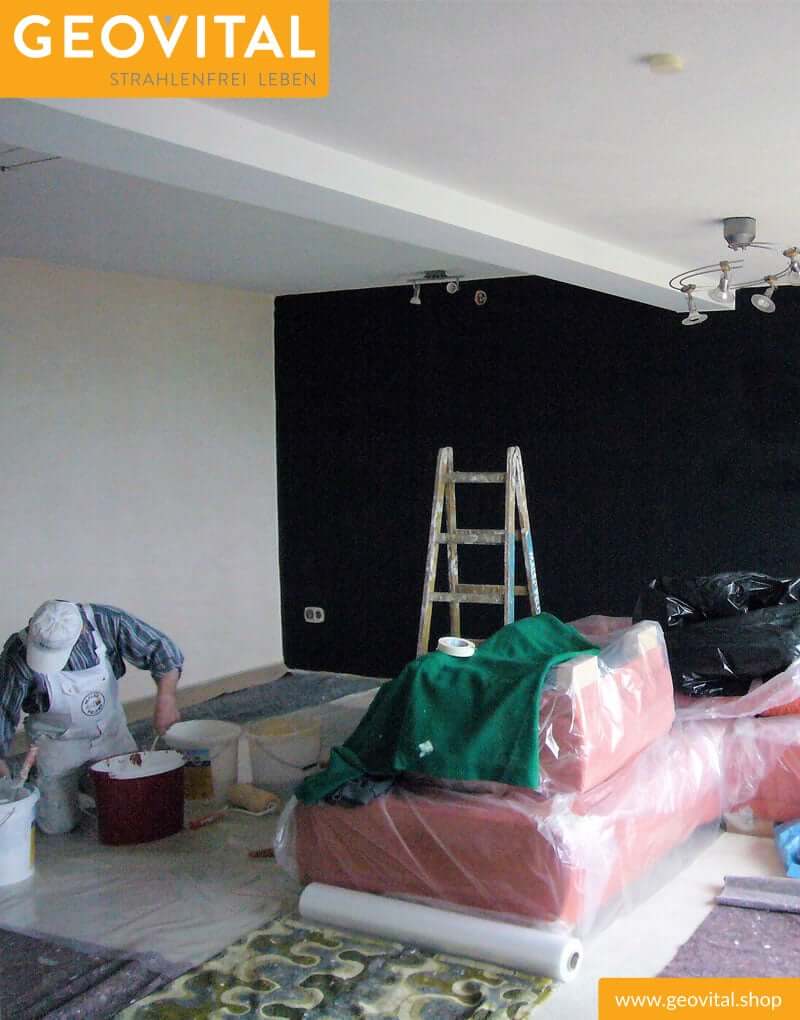 Maler beim Streichen von Wohnzimmer mit T98 Abschirmfarbe